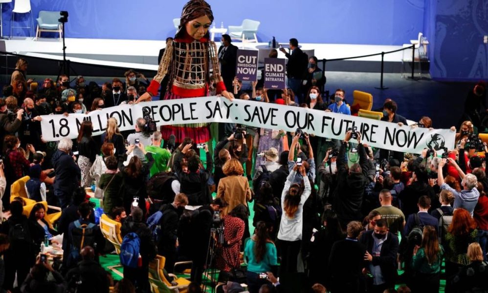 96114257_People-gather-around-Little-Amal-a-35-metre-tall-puppet-of-a-young-Syrian-refugee-girl